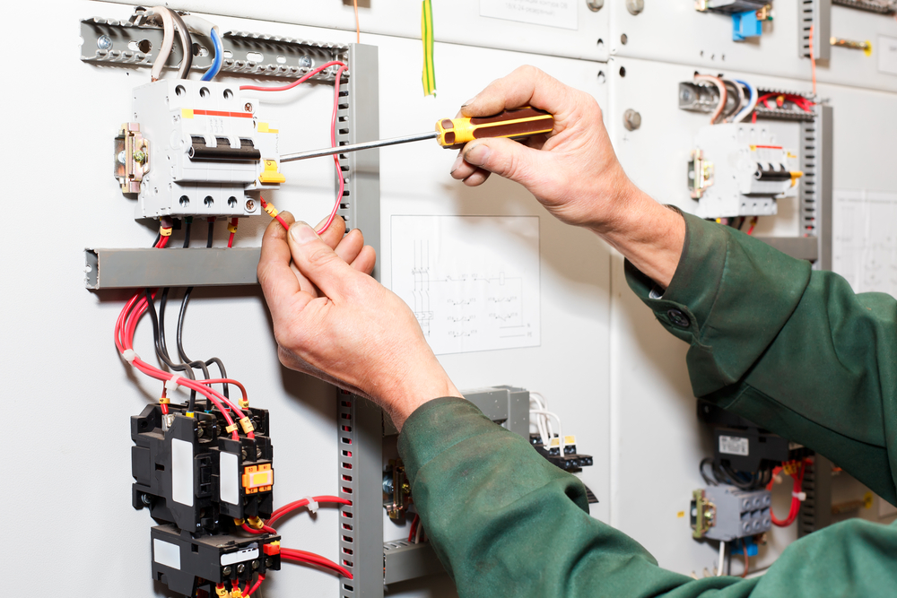 An electricians hands working on an electrical unit.